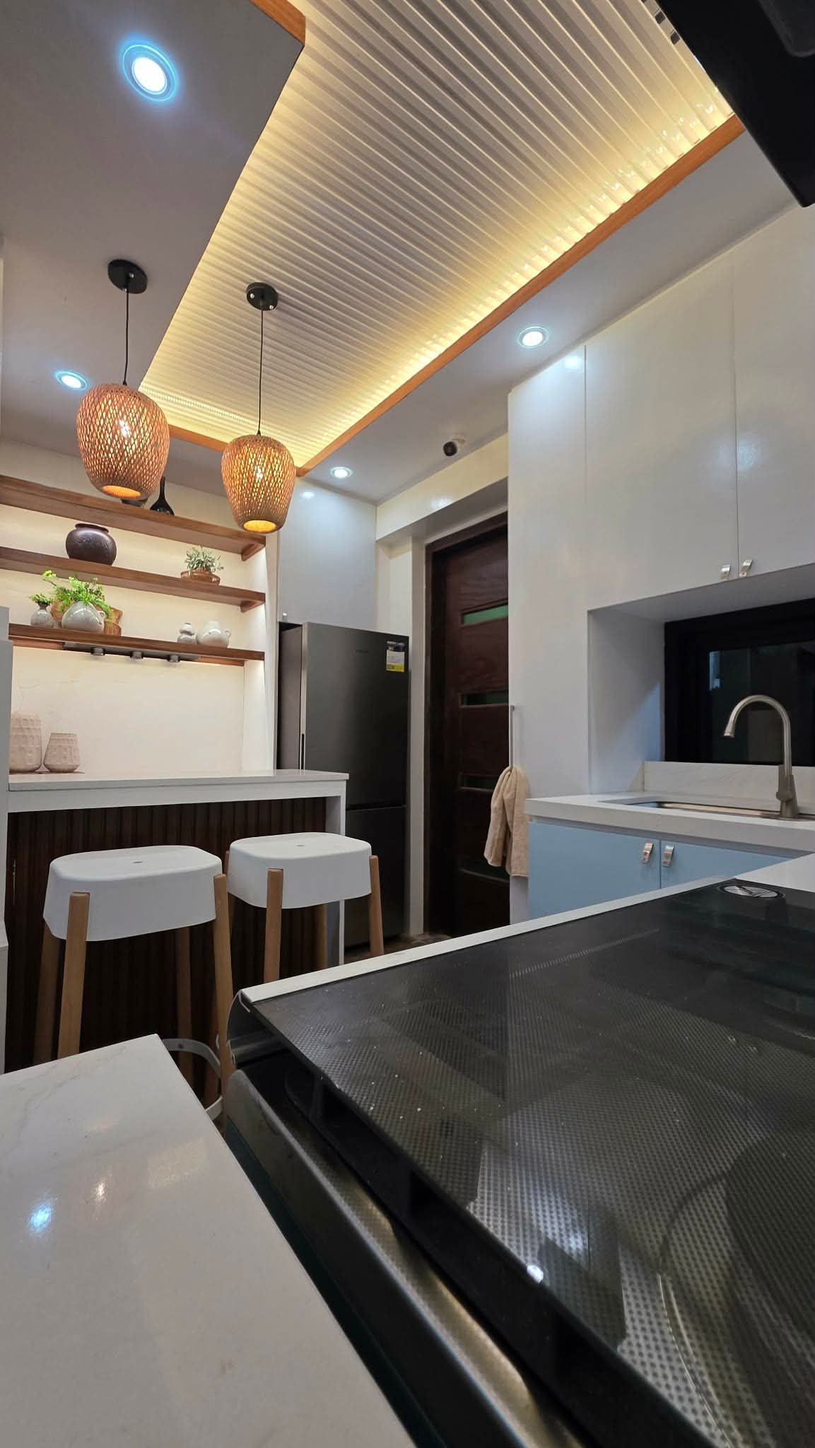 Kitchen counter with rattan pendant lights and wood shelving